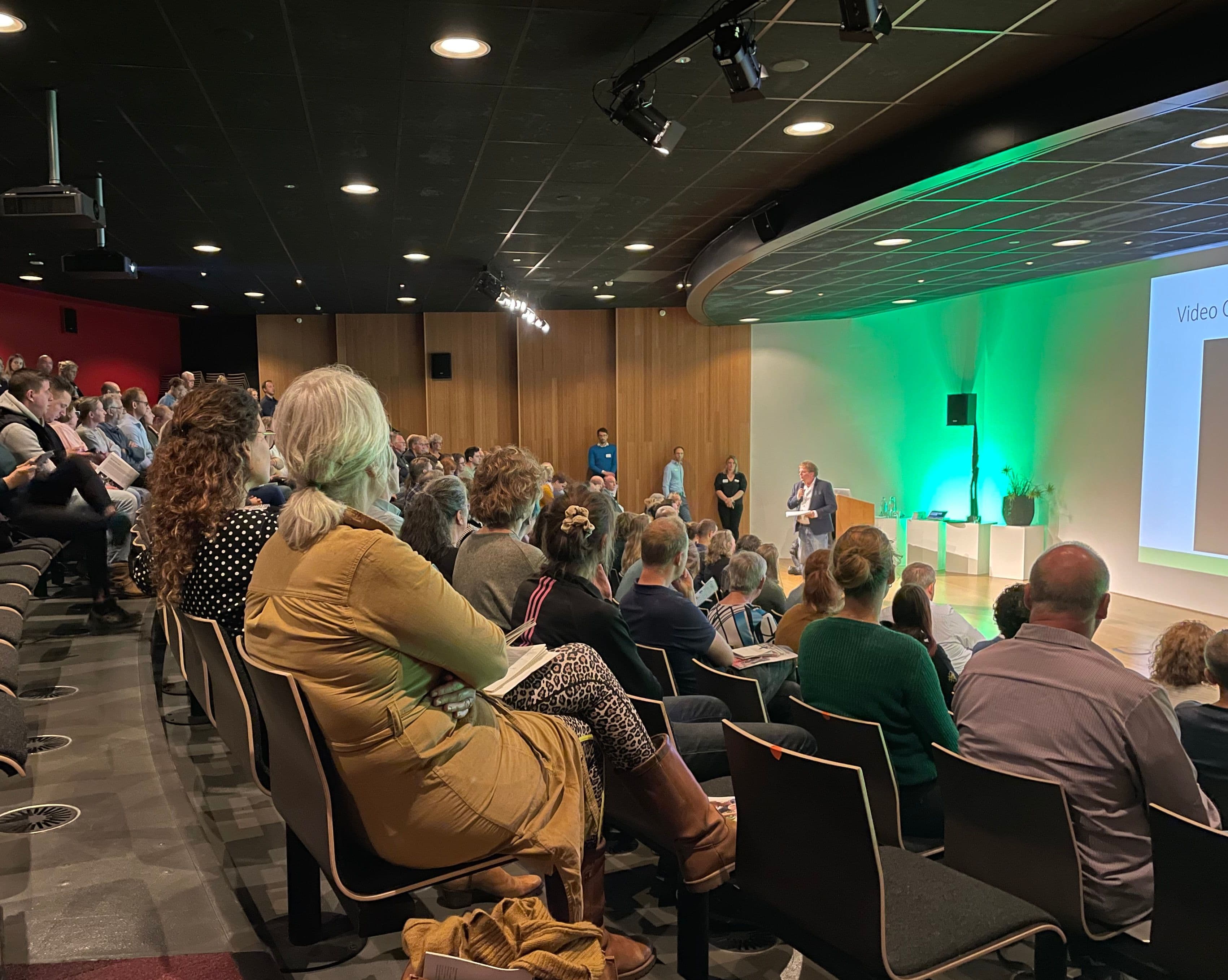 Deelnemers aan het Burgerberaad worden in een theatersetting toegesproken vanaf een podium